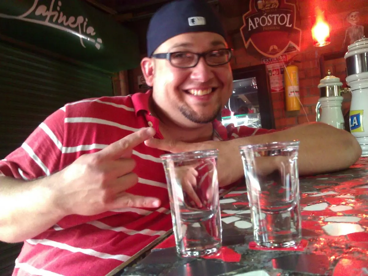 Two small shot glasses of clear aguardiente on a bar, poured neat with no mixer