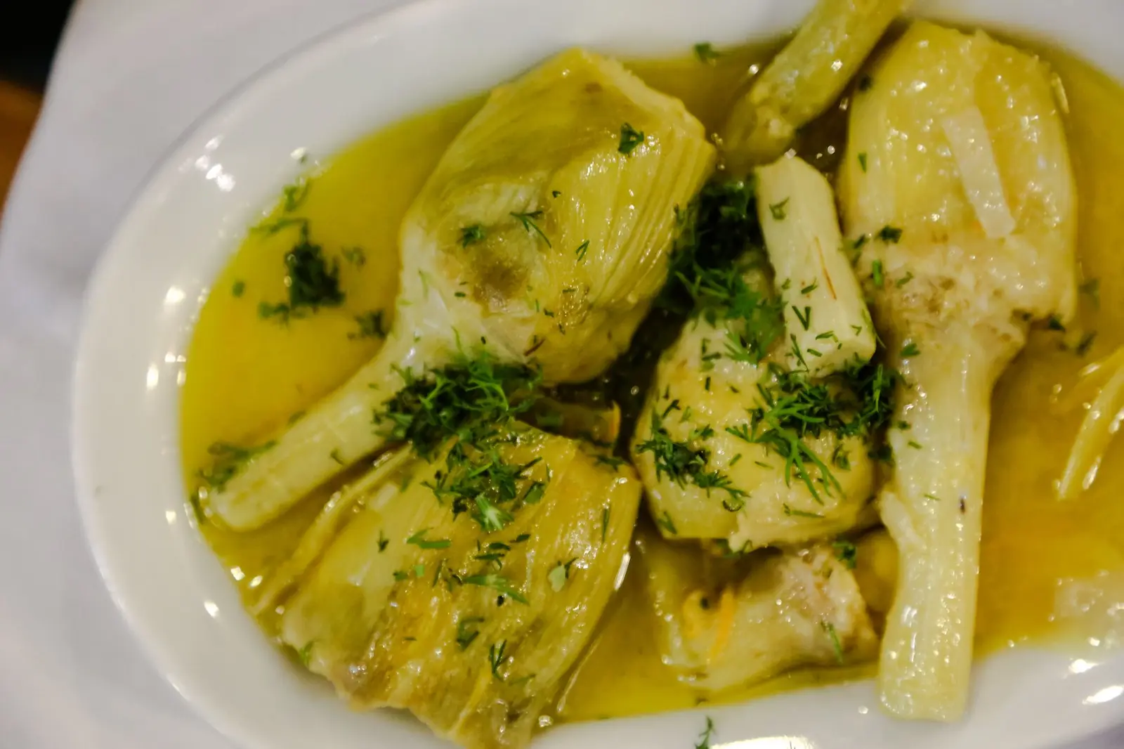 A plate of artichokes braised in olive oil and herbs, in the Roman carciofi alla romana style
