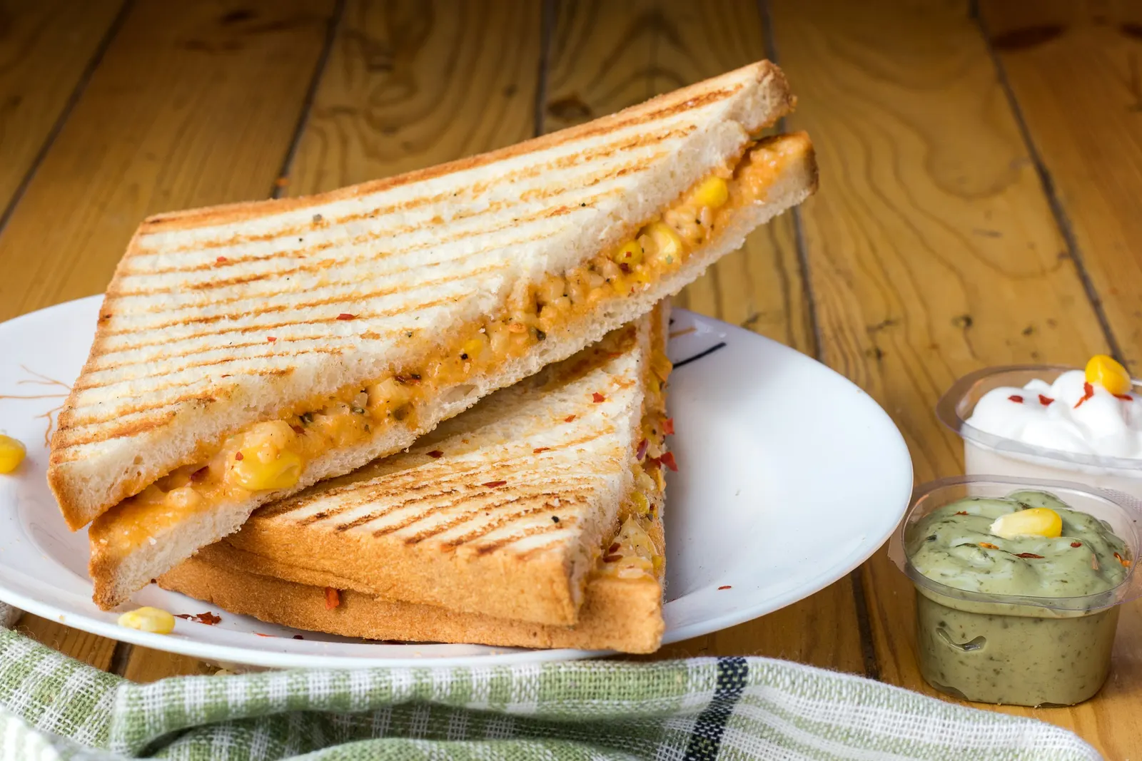 A grilled cheese sandwich, golden and toasted, cut and stacked on a white plate