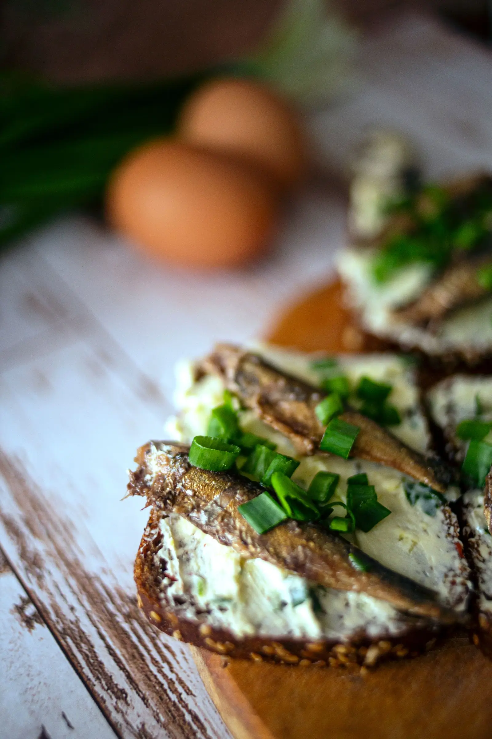 A sardine tartine with cream cheese and spring onions on rustic toasted bread
