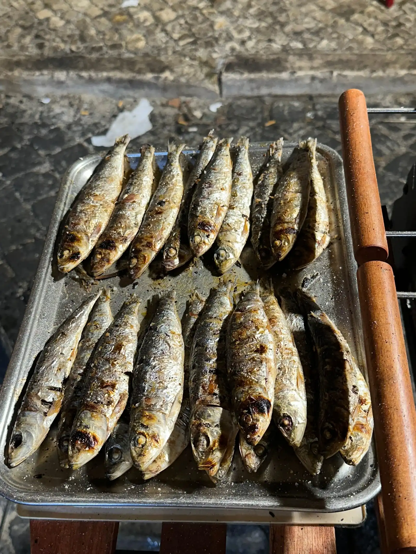 Freshly grilled sardines lined up on a tray, Lisbon street-food style
