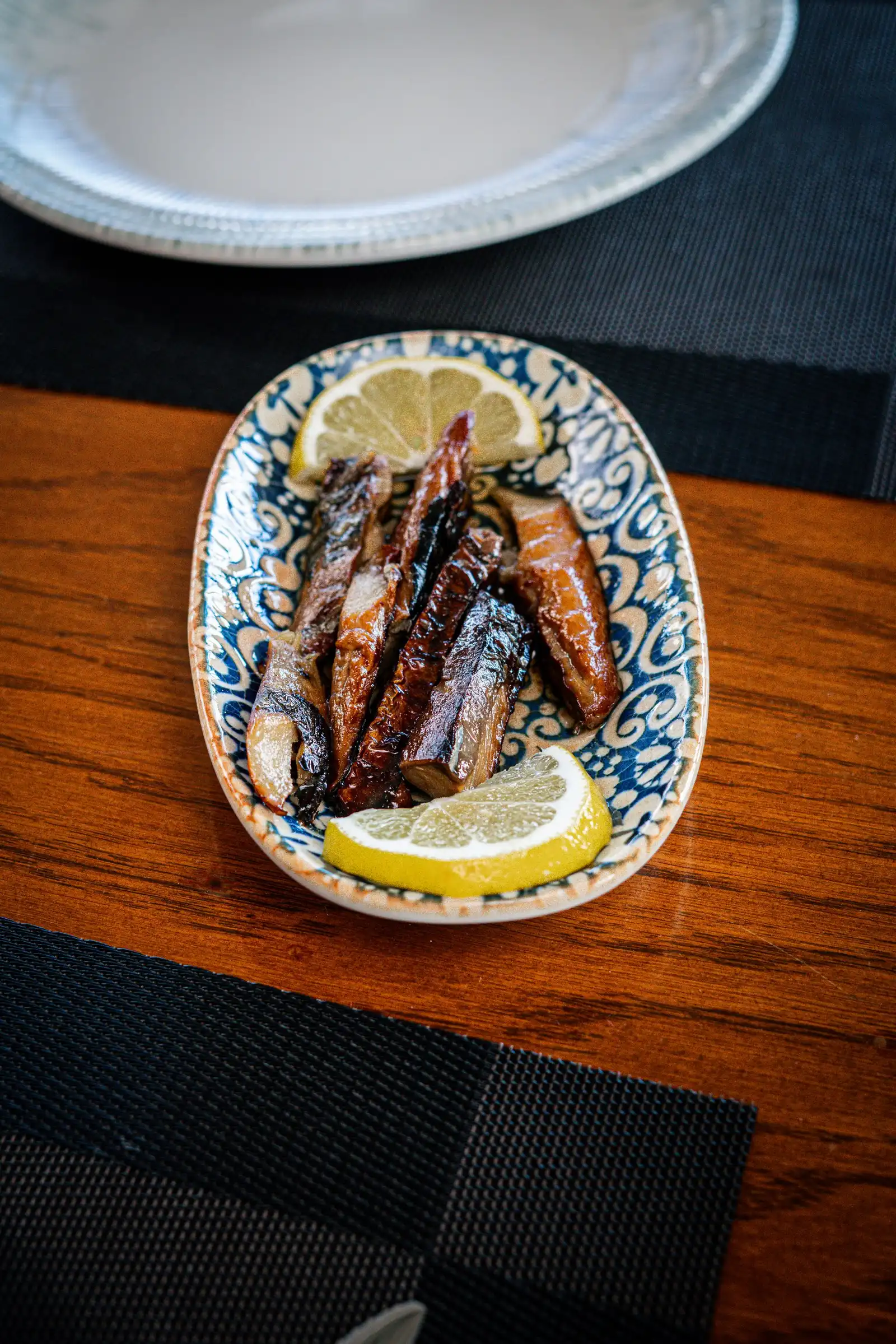 Sardines with lemon slices served hot on a ceramic plate