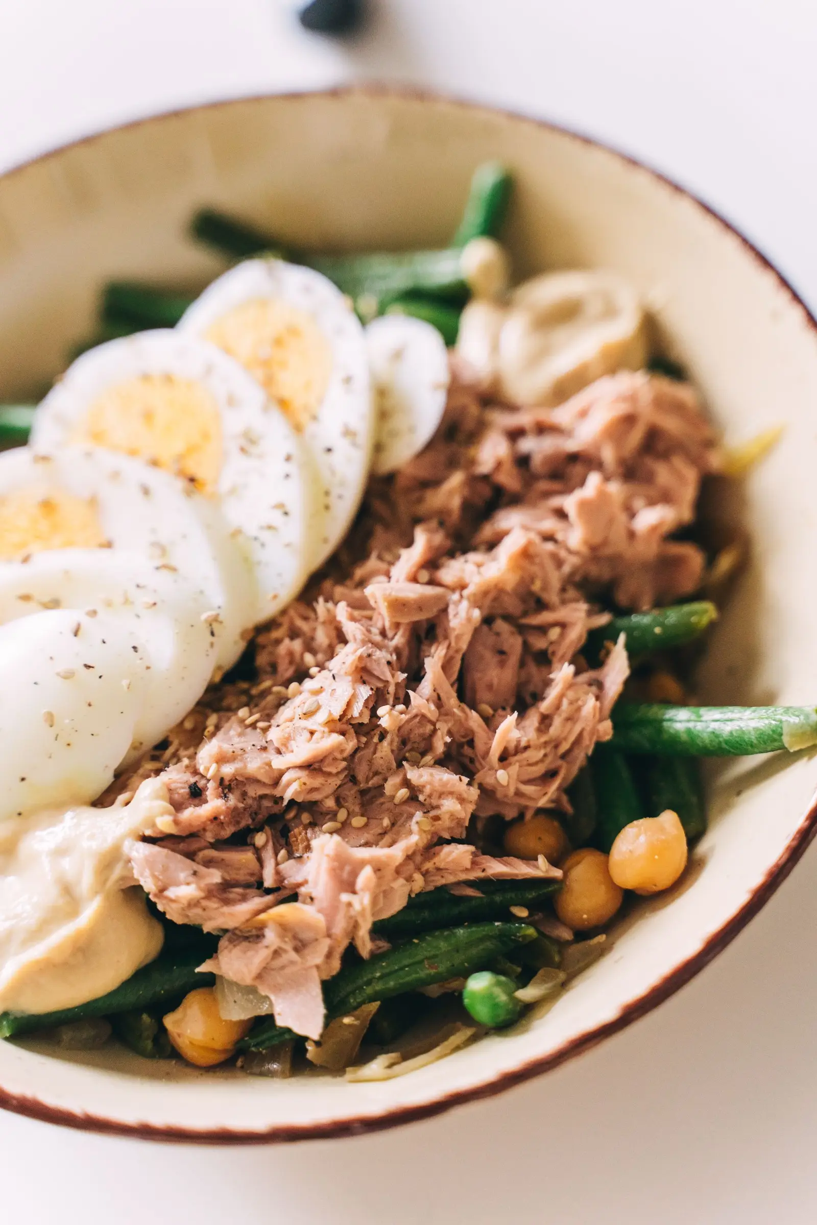 A niçoise-style composed salad with egg, green beans, and chickpeas in a bowl