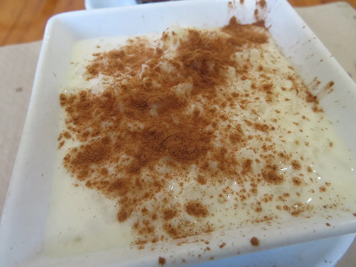 A white dish of arroz con leche rice pudding dusted with cinnamon