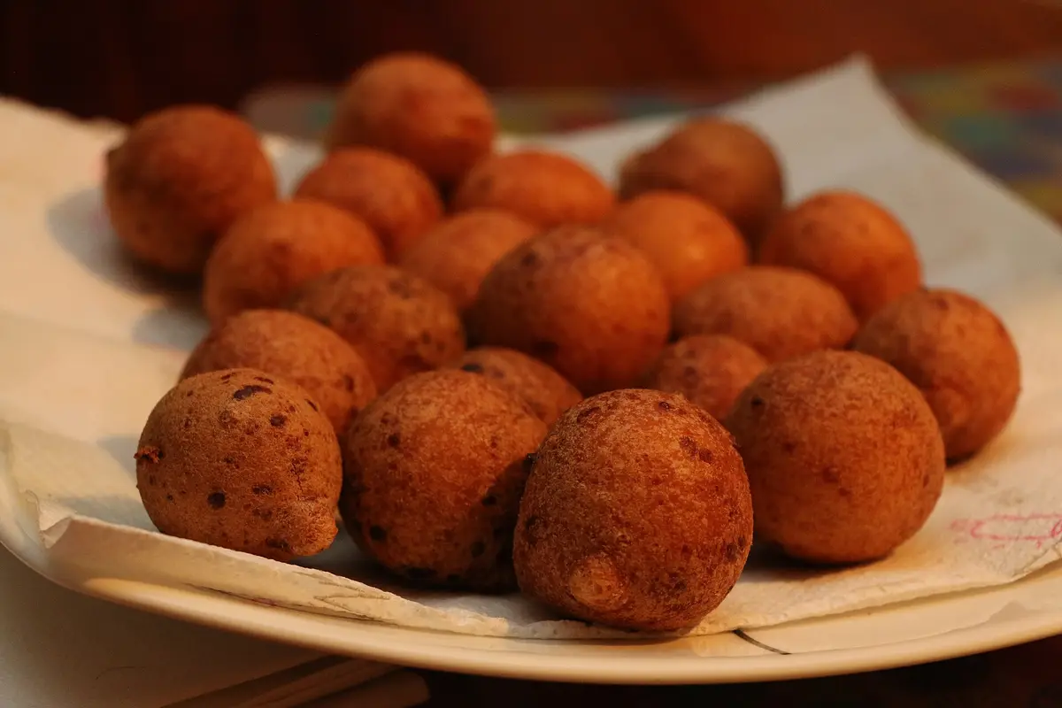 A plate of golden round Colombian buñuelos, fried cheese-dough fritters