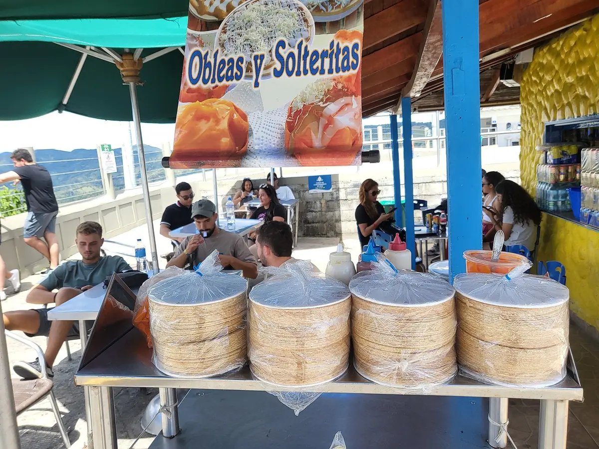 A Colombian street cart selling stacks of obleas wafers under an 'Obleas y Solteritas' sign