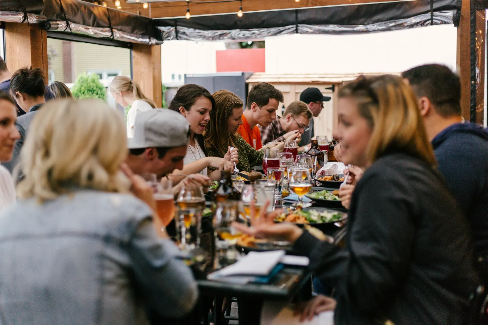 A group of people seated around a table, talking and sharing a meal together