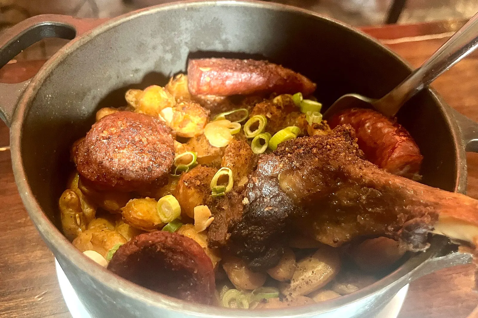 A pot of cassoulet with duck, sausage, and white beans