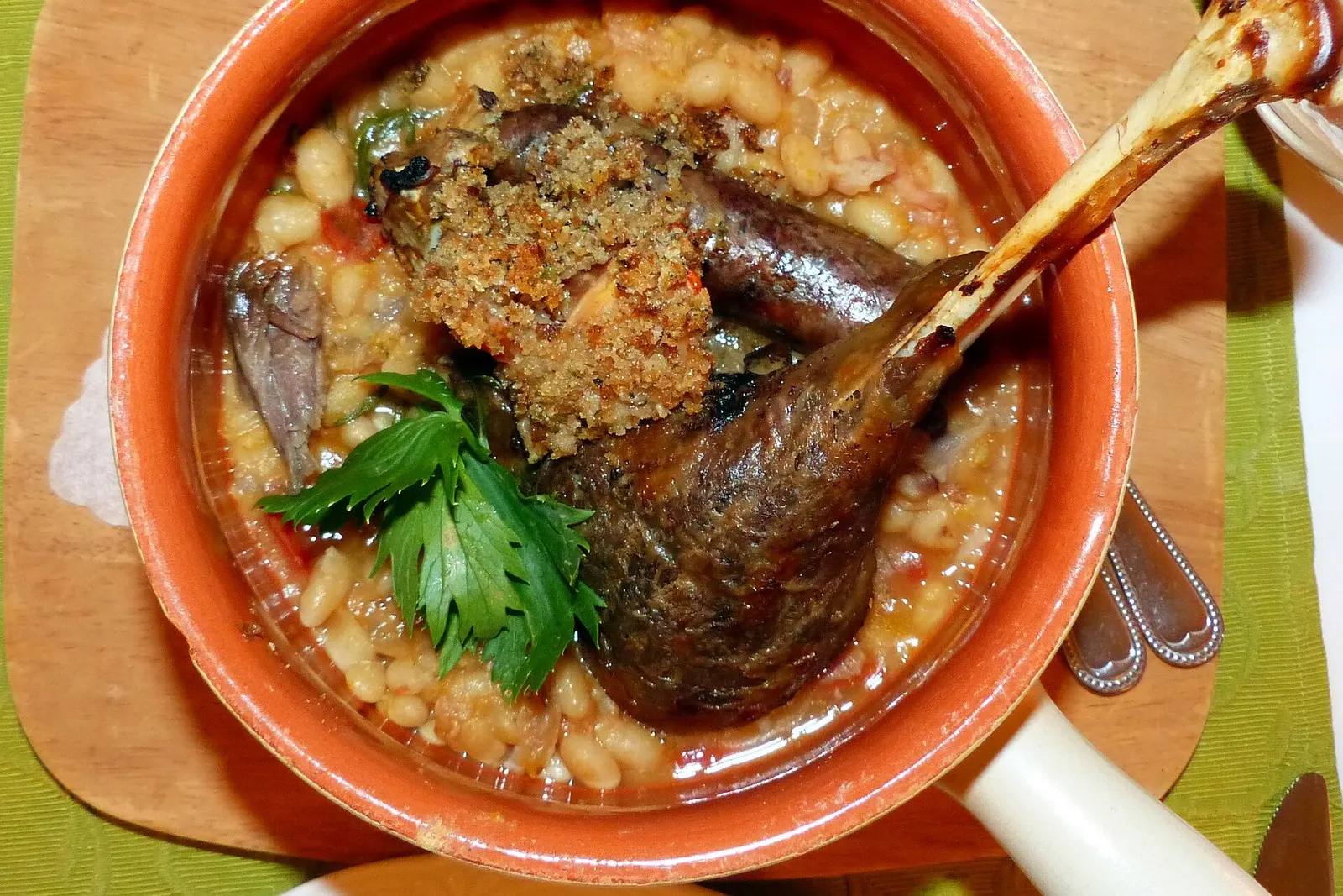 Top-down view of cassoulet showing the breadcrumb crust over white beans and confit