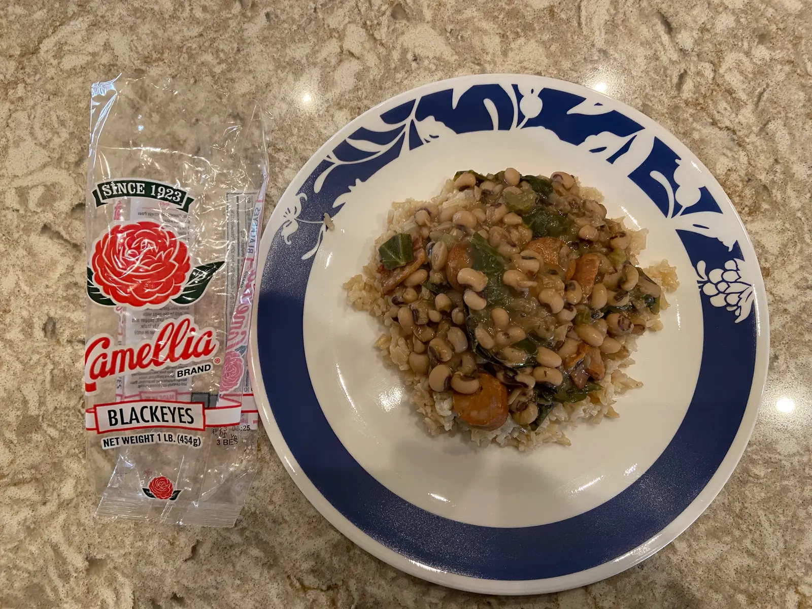 Southern-style black-eyed peas cooked with bacon, sausage and collard greens in a dark pot