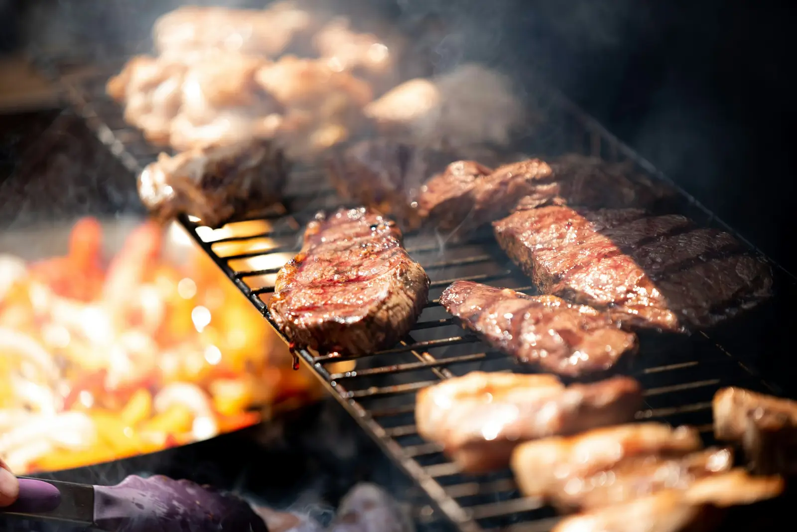 Grilled steak cooking over a hot charcoal barbecue, charring on the grates