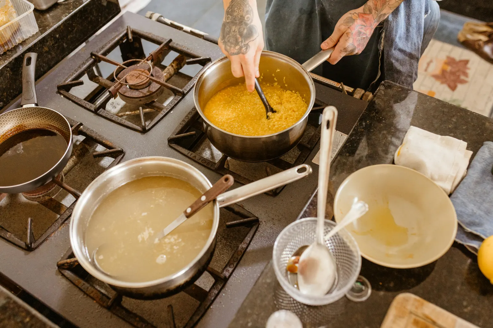 A cook stirring ingredients in a pan on a gas stove, mid-action in a home kitchen