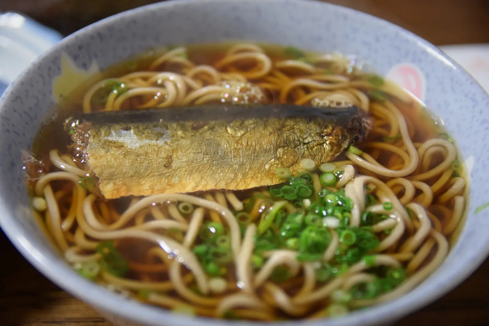 A bowl of toshikoshi soba, buckwheat noodles in dark broth with herring and scallions, eaten in Japan on New Year's Eve