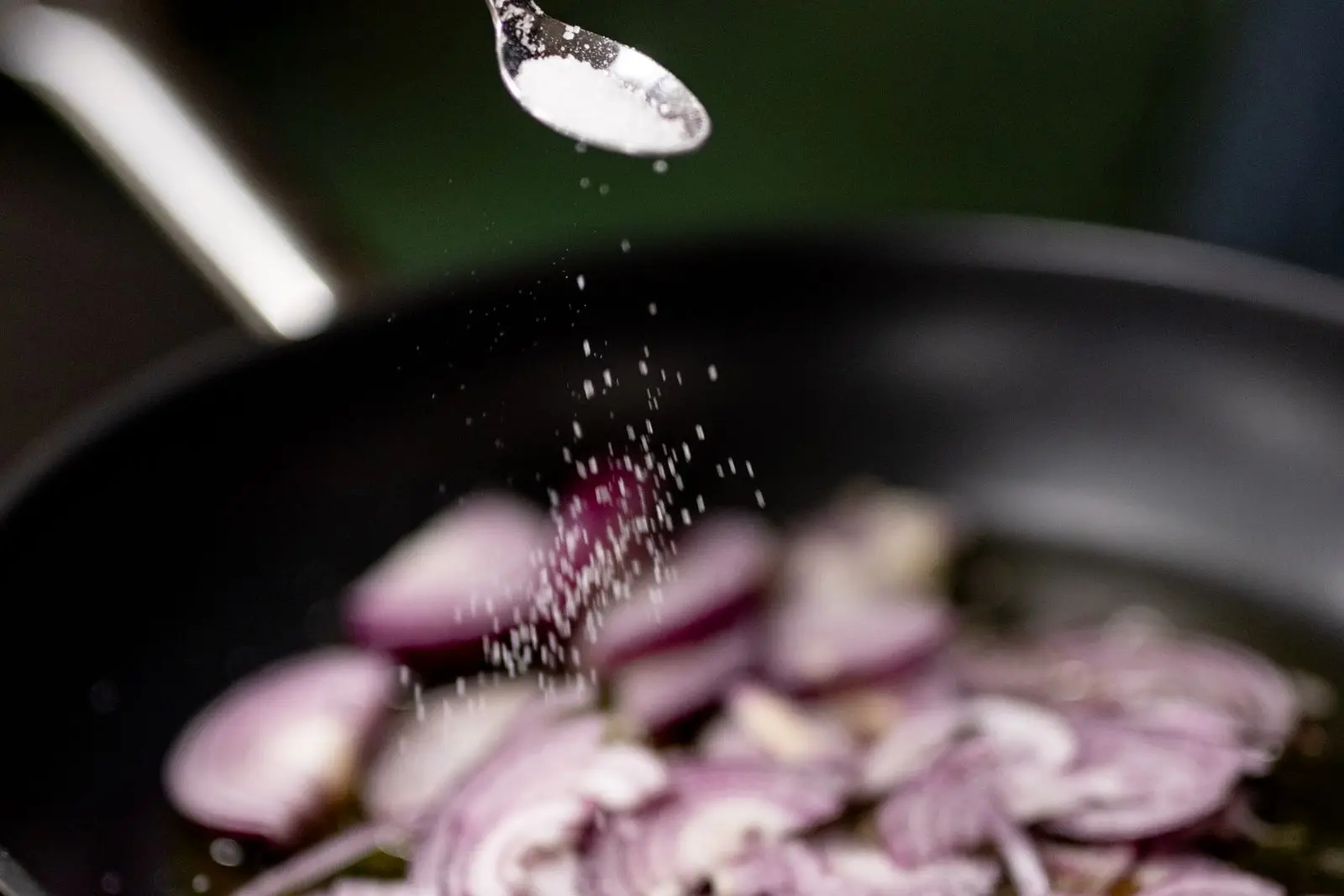 Sliced onions being salted and cooked down slowly in a pan, the key step for pasta alla Genovese