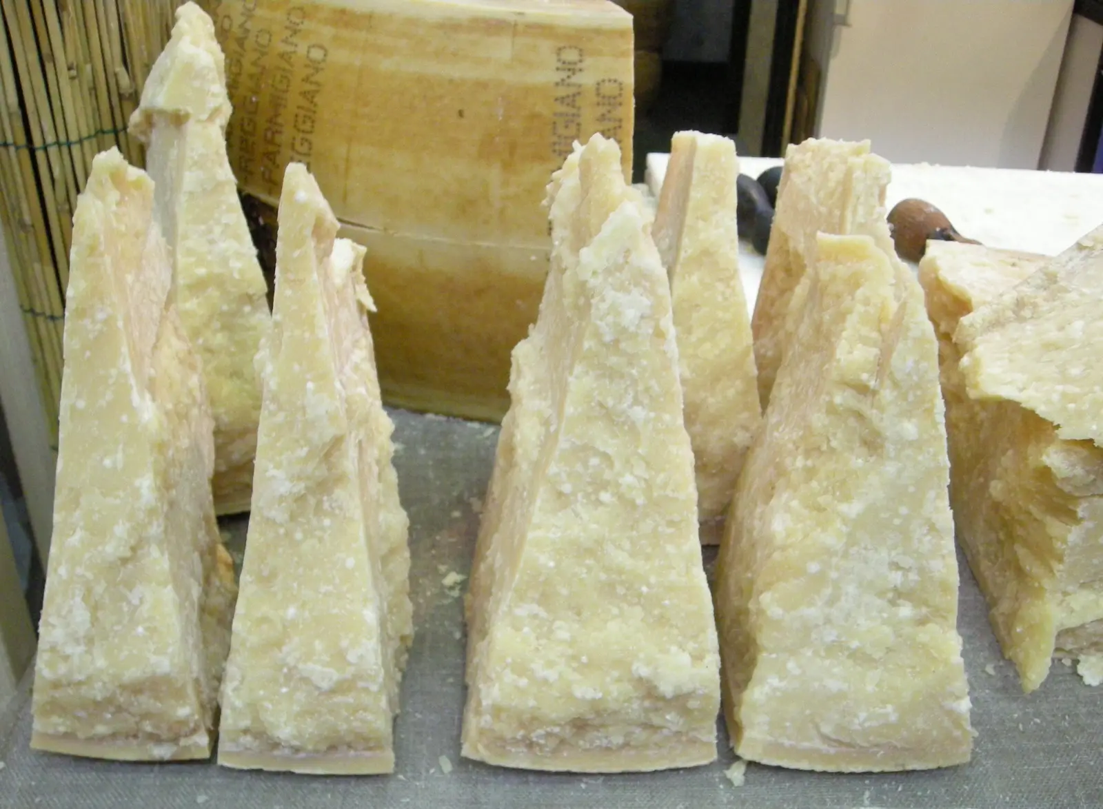 Wedges of Parmigiano-Reggiano cut from a wheel, showing the crystalline pale-gold interior of a cheese aged past two years