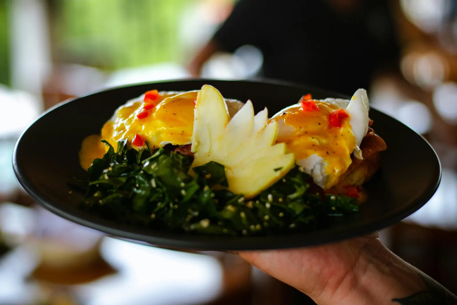 A plated dish of eggs benedict with fresh greens, hollandaise glossy over poached eggs and English muffins, the brunch staple test