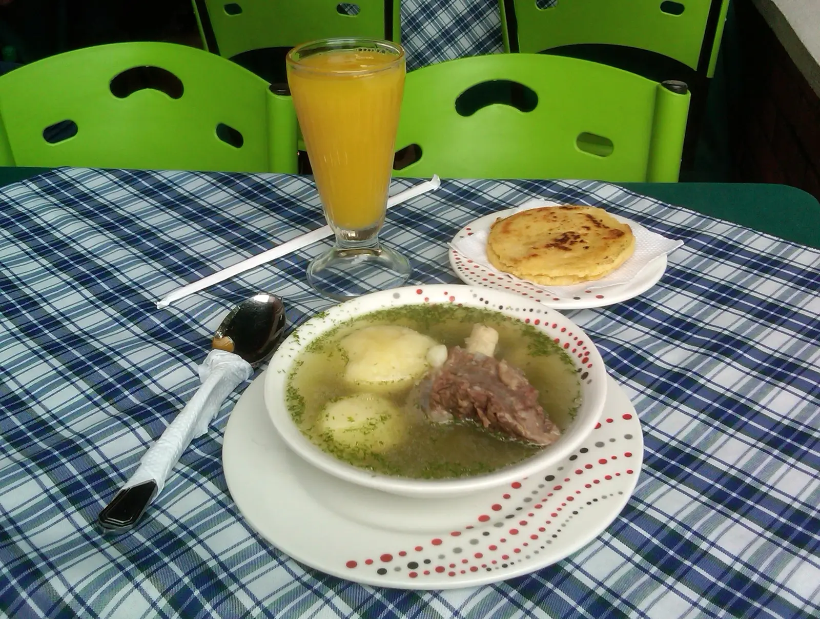 A bowl of caldo de costilla, a clear beef rib broth with potato and cilantro, eaten for breakfast in the cold Colombian highlands
