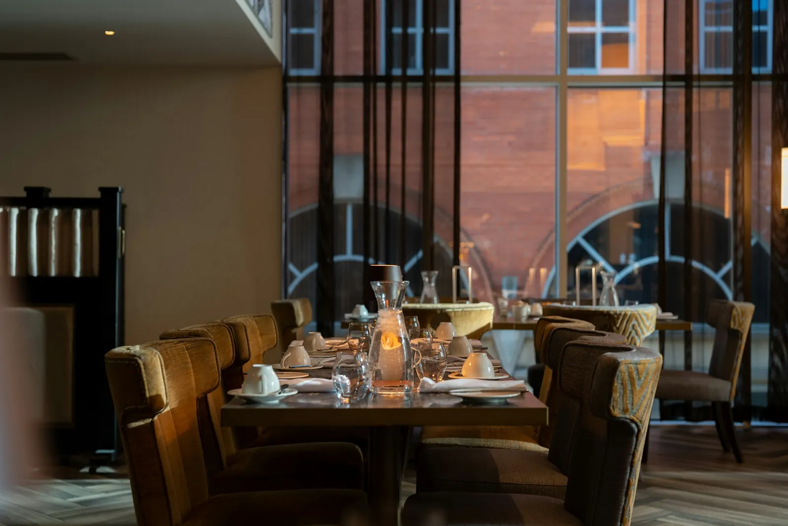 A formally set restaurant table with candles, multiple wine glasses, and cloth napkins, the kind of dining setup that signals a maître d' is running the floor