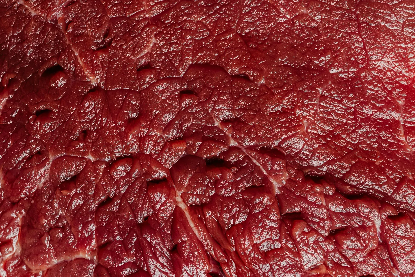 Extreme close-up of raw beef showing the fine white veining of marbling distributed evenly through the deep red muscle
