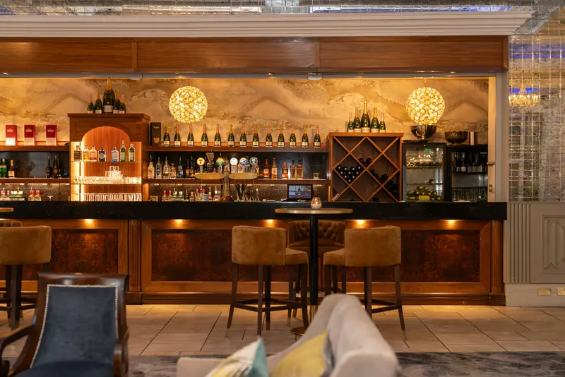 An upscale cocktail bar interior with backlit bottles and empty stools